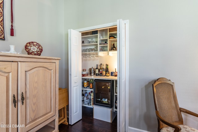 bar with light brown cabinets and dark wood-type flooring