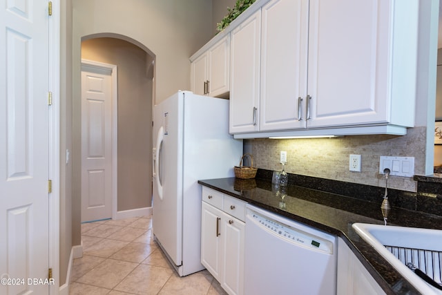 kitchen featuring dark stone counters, white cabinetry, white appliances, and light tile patterned floors