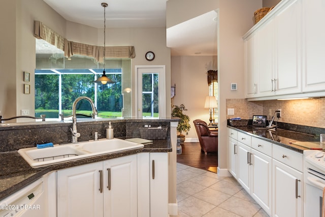 kitchen featuring white cabinetry, sink, dark stone counters, decorative light fixtures, and light hardwood / wood-style flooring