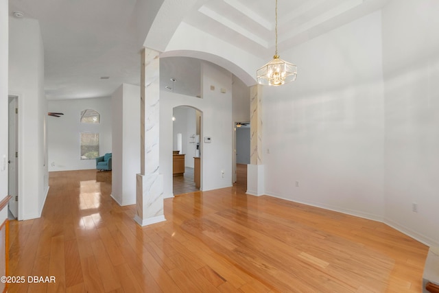 empty room with a chandelier, hardwood / wood-style floors, and a high ceiling