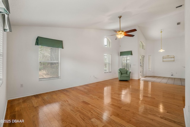 unfurnished living room with ceiling fan, high vaulted ceiling, and light wood-type flooring