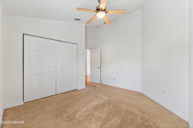 unfurnished bedroom with a towering ceiling, light colored carpet, a closet, and ceiling fan