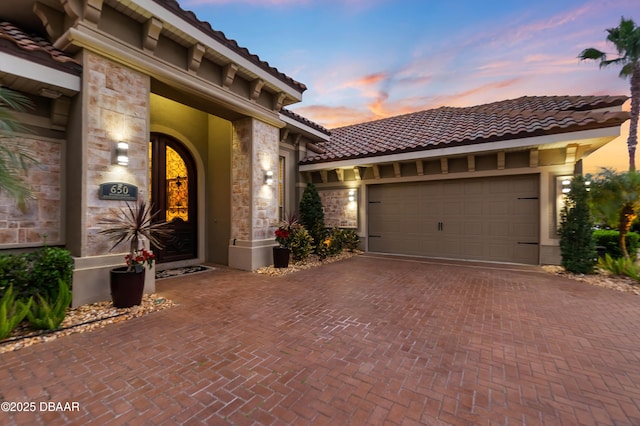 650 Woodbridge Dr, Ormond Beach, FL 32174 - view of front of property featuring a tile roof, stone siding, decorative driveway, a garage, and stucco siding