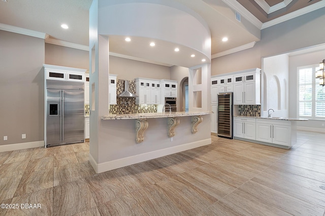 650 Woodbridge Dr, Ormond Beach, FL 32174 - kitchen with stainless steel appliances, wine cooler, ornamental molding, a breakfast bar, and wall chimney exhaust hood