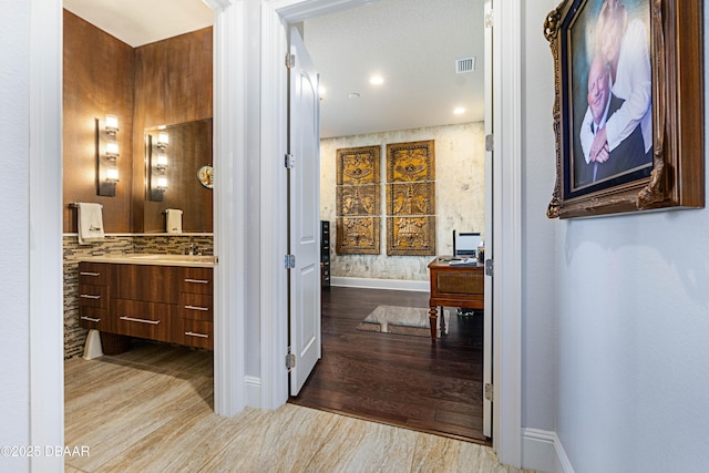 650 Woodbridge Dr, Ormond Beach, FL 32174 - hallway featuring wood finished floors, baseboards, and a sink
