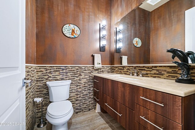 650 Woodbridge Dr, Ormond Beach, FL 32174 - half bath with vanity, toilet, tile walls, and decorative backsplash