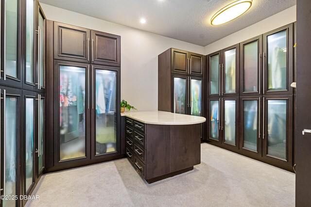 650 Woodbridge Dr, Ormond Beach, FL 32174 - kitchen with a peninsula, light countertops, light carpet, glass insert cabinets, and a textured ceiling