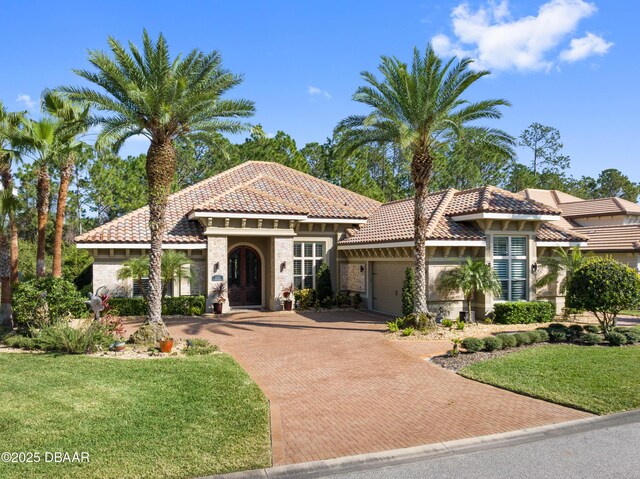 650 Woodbridge Dr, Ormond Beach, FL 32174 - mediterranean / spanish home featuring an attached garage, decorative driveway, stone siding, and a tiled roof