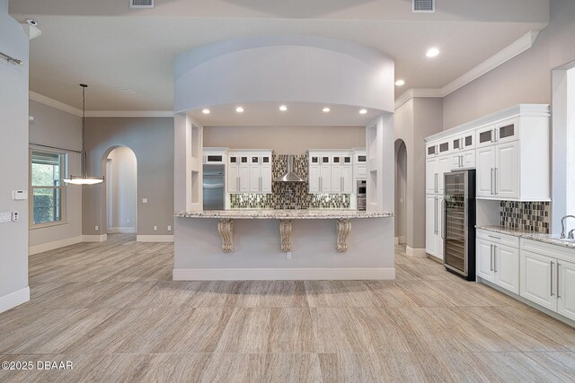 650 Woodbridge Dr, Ormond Beach, FL 32174 - kitchen featuring arched walkways, wall chimney range hood, beverage cooler, decorative backsplash, and ornamental molding