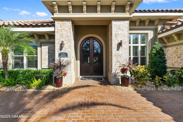 650 Woodbridge Dr, Ormond Beach, FL 32174 - entrance to property with stone siding, a tile roof, stucco siding, and french doors