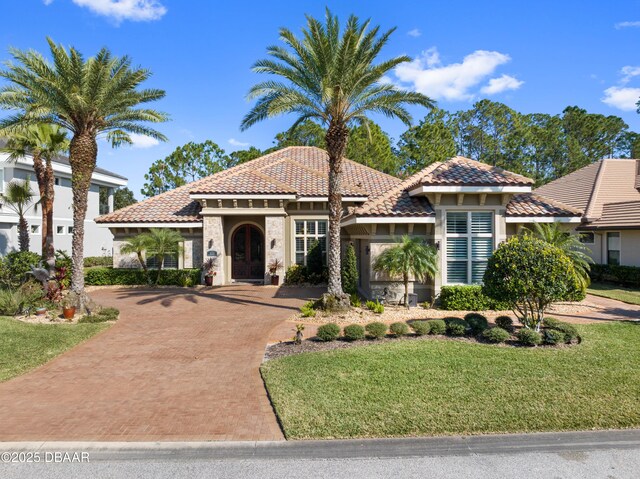 650 Woodbridge Dr, Ormond Beach, FL 32174 - mediterranean / spanish home featuring decorative driveway, a tile roof, a front lawn, and stucco siding
