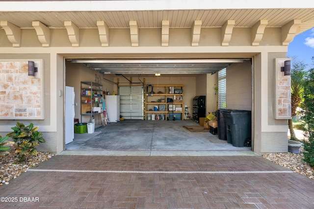 650 Woodbridge Dr, Ormond Beach, FL 32174 - garage featuring decorative driveway and freestanding refrigerator