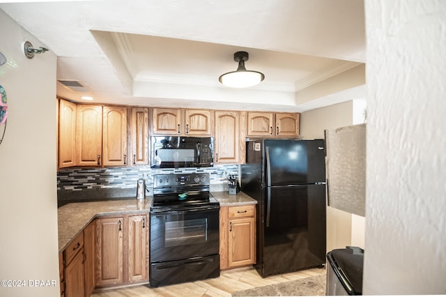 kitchen featuring light wood-type flooring, light stone countertops, black appliances, and decorative backsplash