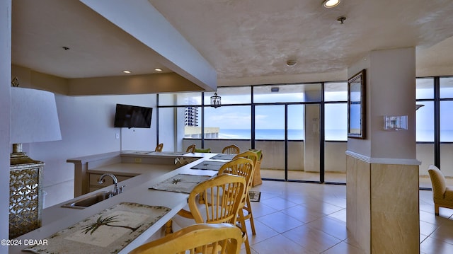 interior space featuring a wealth of natural light, sink, light tile patterned floors, and a wall of windows