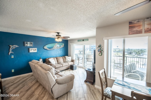 living room featuring ceiling fan, a textured ceiling, and light wood-type flooring