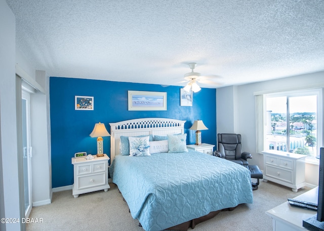 bedroom featuring ceiling fan, a textured ceiling, and light colored carpet