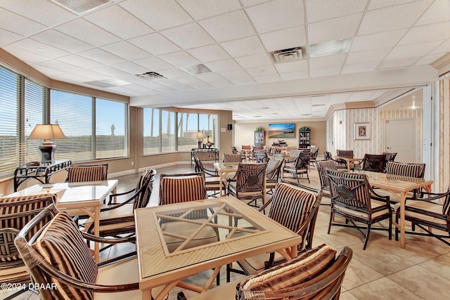 dining room featuring a paneled ceiling and light tile patterned flooring