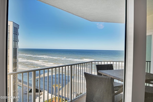 balcony featuring a view of the beach and a water view