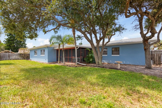 back of property with a sunroom and a yard