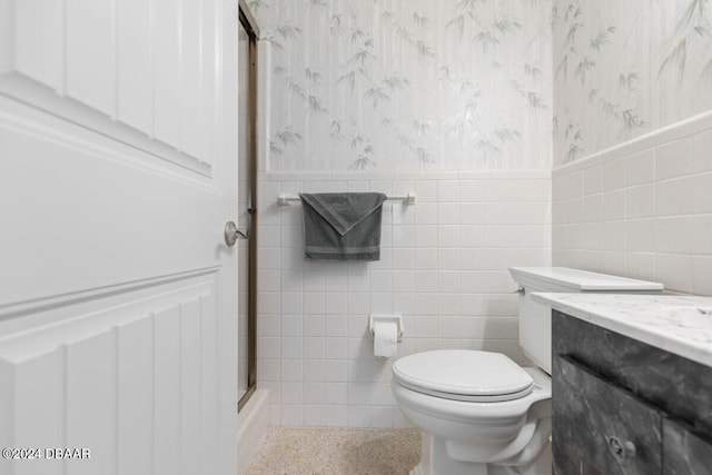 bathroom with toilet, vanity, and tile walls