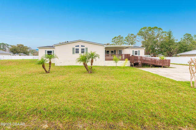 back of property with a yard, fence, and a deck