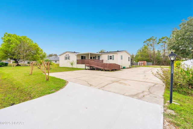 manufactured / mobile home featuring driveway, a front lawn, and a wooden deck