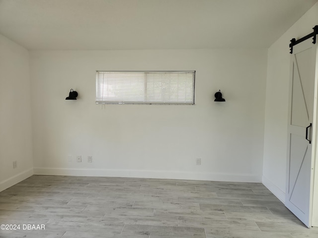 spare room featuring light hardwood / wood-style floors and a barn door