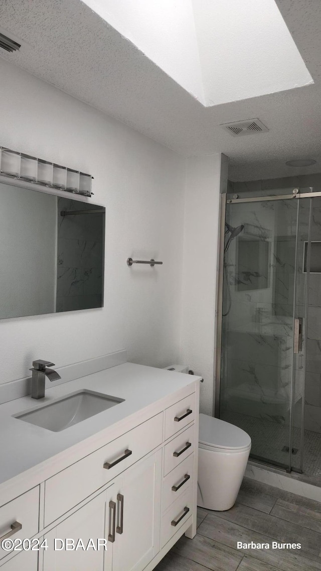 bathroom featuring walk in shower, vanity, a textured ceiling, hardwood / wood-style floors, and toilet