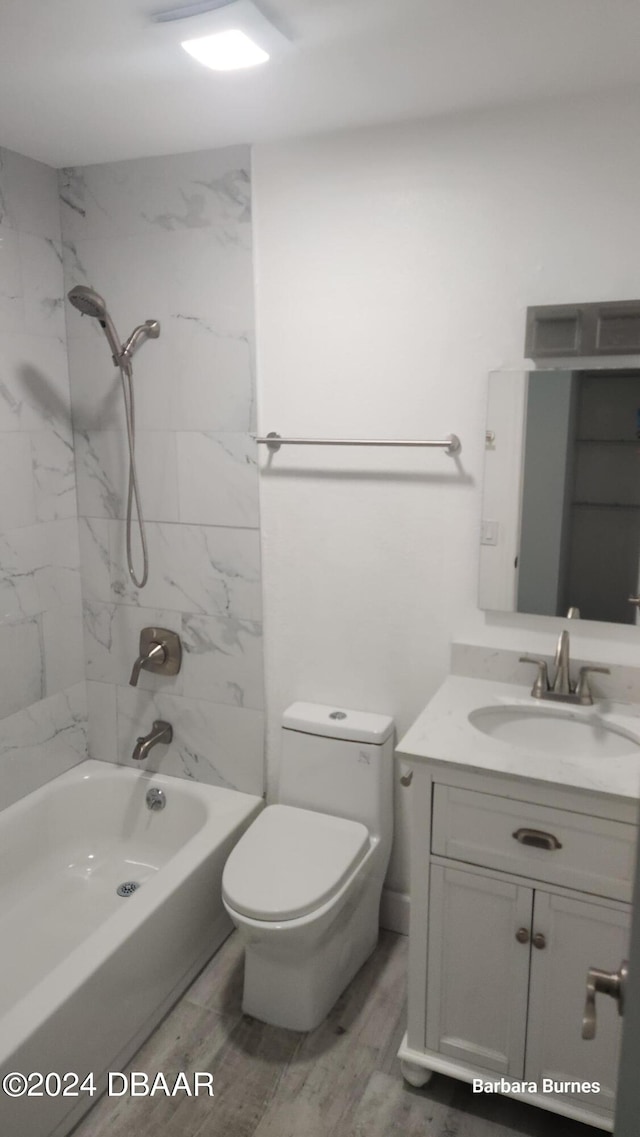 full bathroom featuring wood-type flooring, vanity, toilet, and tiled shower / bath combo