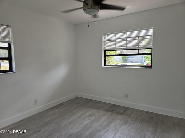 spare room featuring light wood-type flooring, ceiling fan, and a healthy amount of sunlight