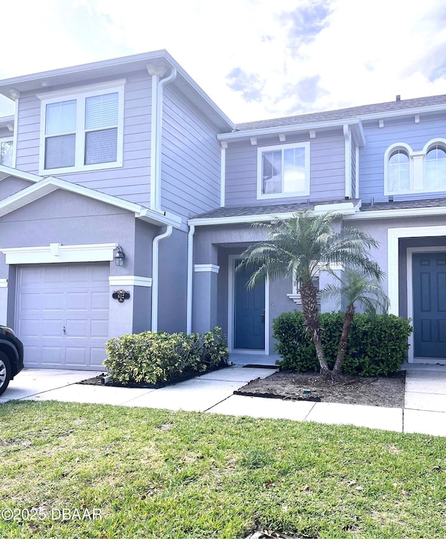 view of front of property featuring an attached garage, a front yard, and stucco siding