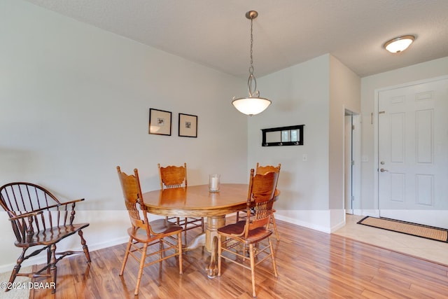 dining space featuring a textured ceiling, light wood finished floors, and baseboards