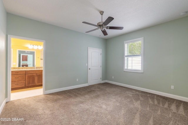 unfurnished bedroom with ceiling fan, light colored carpet, connected bathroom, and a textured ceiling