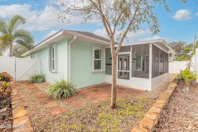 rear view of property featuring a sunroom and a patio