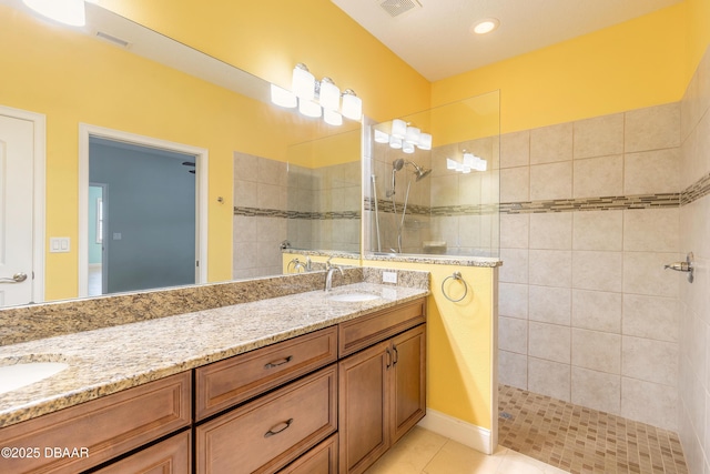 bathroom featuring vanity, a tile shower, and tile patterned flooring