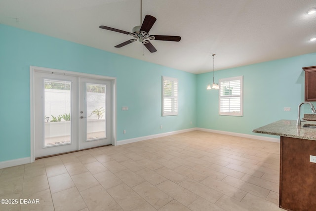 interior space with ceiling fan with notable chandelier, a textured ceiling, french doors, sink, and light tile patterned flooring