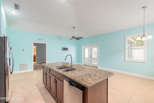 kitchen featuring appliances with stainless steel finishes, a kitchen island with sink, pendant lighting, light stone counters, and sink