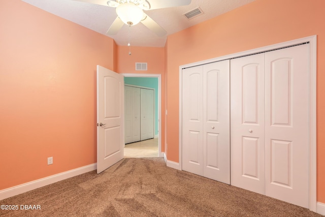 unfurnished bedroom with a textured ceiling, ceiling fan, a closet, and carpet floors