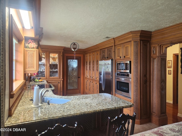 kitchen with light stone countertops, appliances with stainless steel finishes, and sink