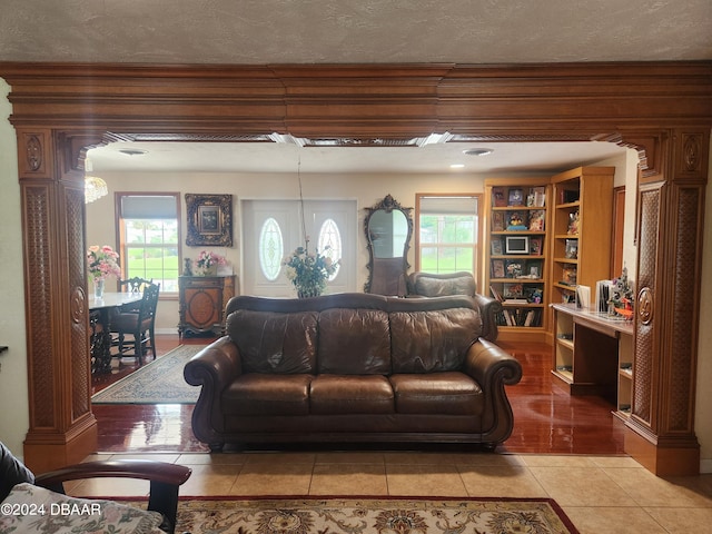 living room with a wealth of natural light, a textured ceiling, and light tile patterned floors