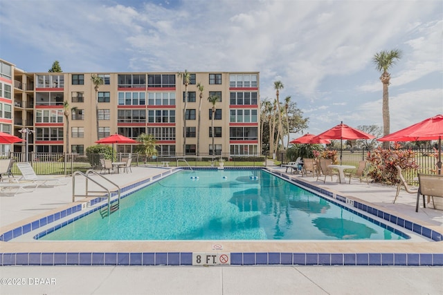 community pool with a patio area and fence