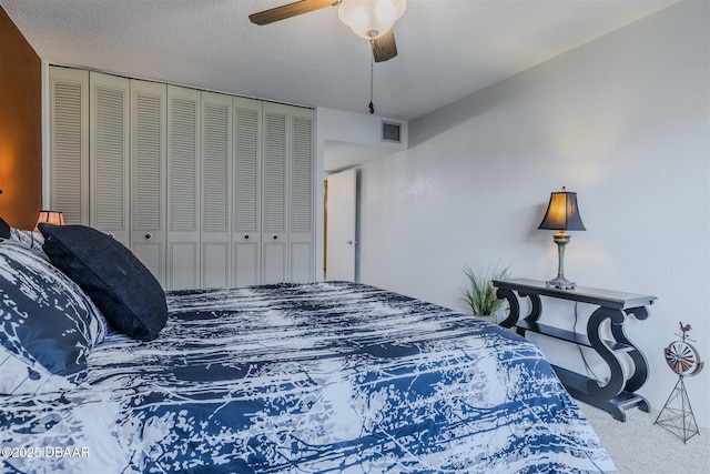 carpeted bedroom featuring a ceiling fan, a textured ceiling, visible vents, and a closet