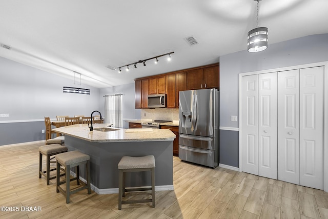 133 Brasswood Ct, Daytona Beach, FL 32117 - kitchen with light wood finished floors, a breakfast bar, a sink, stainless steel appliances, and rail lighting
