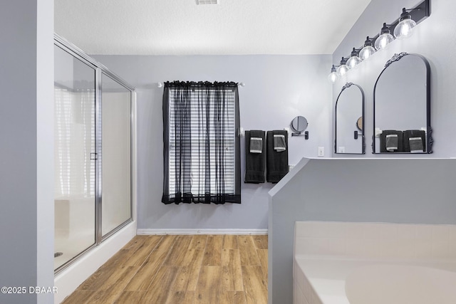 133 Brasswood Ct, Daytona Beach, FL 32117 - bathroom with baseboards, wood finished floors, a stall shower, and a bathing tub
