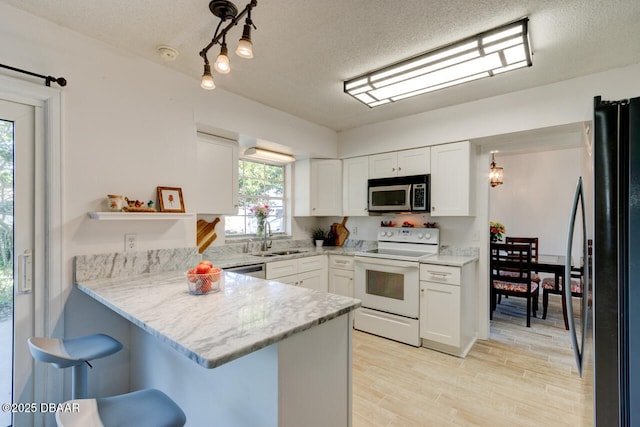 kitchen with stainless steel appliances, sink, white cabinets, a textured ceiling, and kitchen peninsula