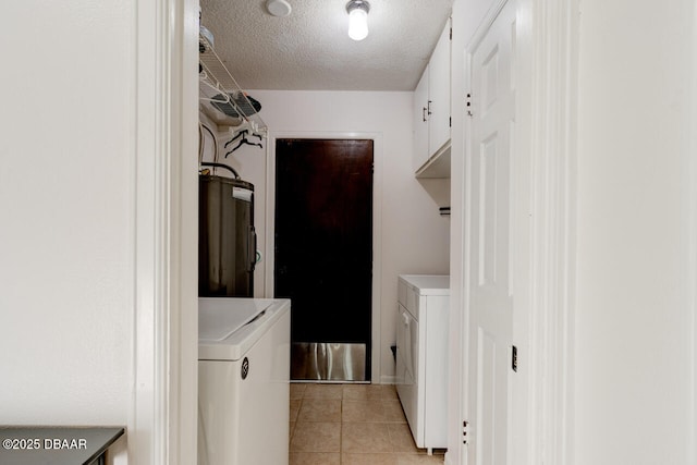 laundry area featuring cabinets, light tile patterned floors, water heater, a textured ceiling, and washing machine and clothes dryer