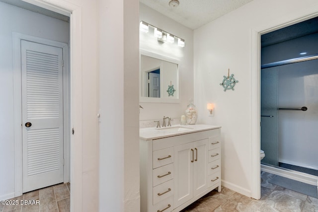 bathroom with a textured ceiling, vanity, and toilet