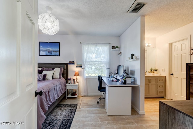 bedroom with a textured ceiling and ensuite bath