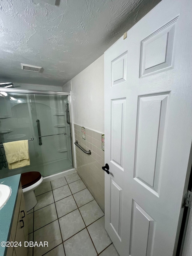 bathroom featuring walk in shower, tile walls, a textured ceiling, and tile patterned flooring