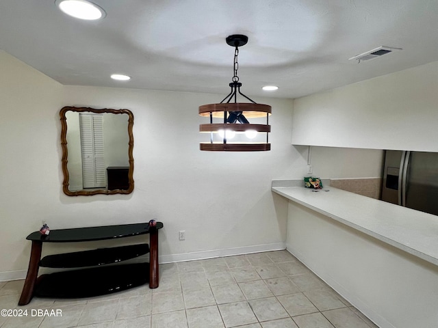 interior space with hanging light fixtures, light tile patterned flooring, and stainless steel fridge with ice dispenser